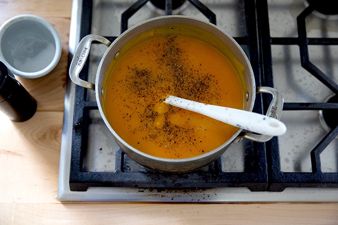 Uma panela de sopa cheia de sopa de abóbora assada e temperada com pimenta.